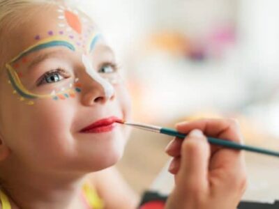 Cute little girl having her face painted for Halloween party. Halloween or carnival family lifestyle background. Face painting, headshot close up.