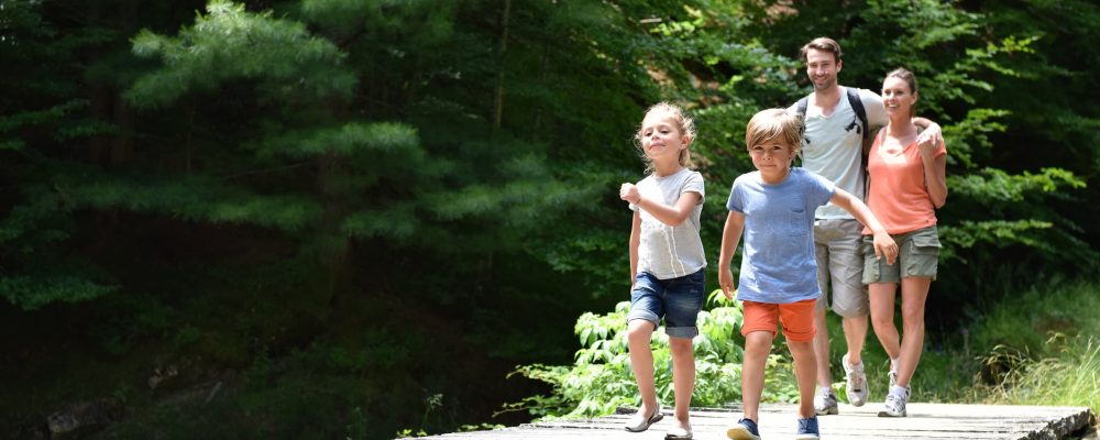 Family of four walking on a bridge crossing the river