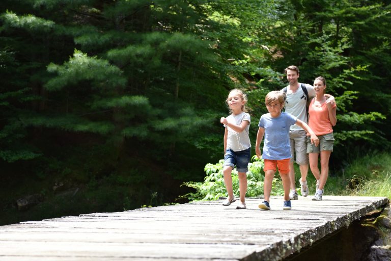 Family of four walking on a bridge crossing the river