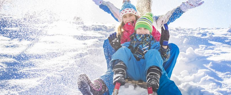 Happy family having fun together on the snowy mountain, on a sled.